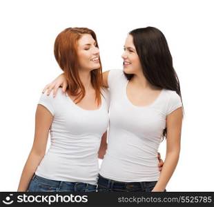friendship, t-shirt designe and happy people concept - two laughing girls in white blank t-shirts looking at each other