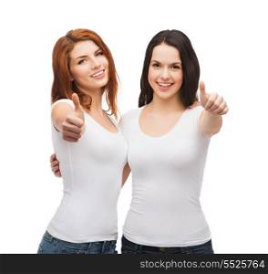 friendship, t-shirt designe and happy people concept - two smiling girls in white blank t-shirts showing thumbs up