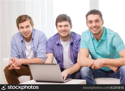 friendship, technology and home concept - smiling male friends with laptop computer at home
