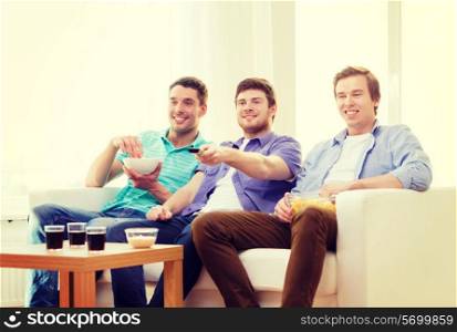 friendship, technology and home concept - smiling male friends with remote control and junk food at home