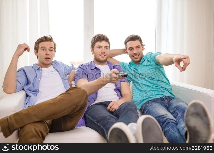 friendship, technology and home concept - smiling male friends with remote control at home
