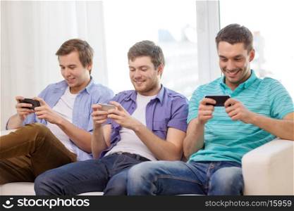 friendship, technology and home concept - smiling male friends with smartphones at home