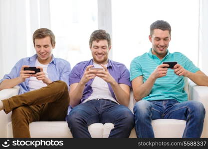 friendship, technology and home concept - smiling male friends with smartphones at home