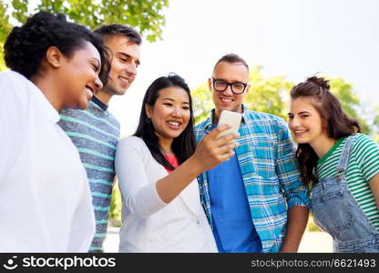 friendship, technology and international concept - group of friends with smartphone at summer park. happy friends with smartphone at summer park