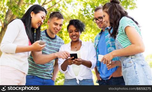 friendship, technology and international concept - group of friends with smartphones at summer park. happy friends with smartphones at summer park