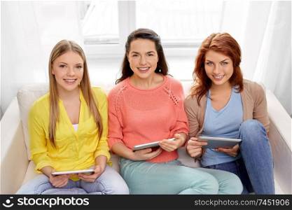 friendship, technology and internet concept - three smiling teenage girls or friends with tablet pc computers at home. three smiling teenage girls with tablet pc at home