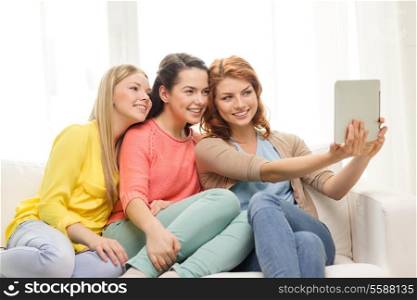 friendship, technology and internet concept - three smiling teenage girls taking picture with tablet pc computer camera at home