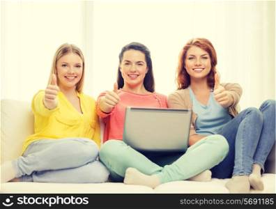 friendship, technology and internet concept - three smiling teenage girls with laptop computer at home