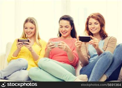 friendship, technology and internet concept - three smiling teenage girls with smartphones at home
