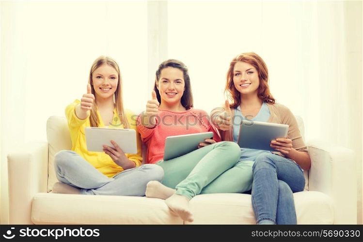 friendship, technology and internet concept - three smiling teenage girls with tablet pc computers at home showing thumbs up