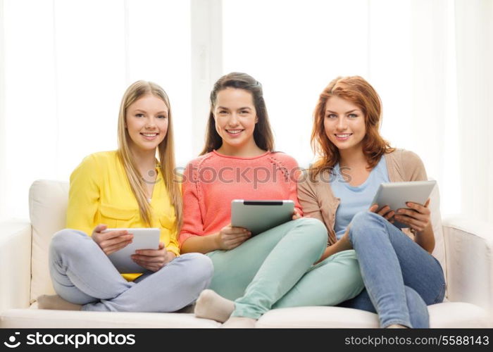 friendship, technology and internet concept - three smiling teenage girls with tablet pc computers at home