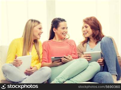 friendship, technology and internet concept - three smiling teenage girls with tablet pc computers at home