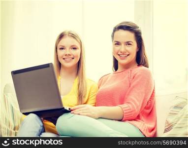 friendship, technology and internet concept - two smiling teenage girls with laptop computer at home