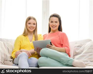 friendship, technology and internet concept - two smiling teenage girls with tablet pc computer at home