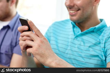 friendship, technology and people concept - close up of happy smiling male friends with smartphones texting at home