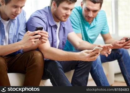 friendship, technology and people concept - close up of happy smiling male friends with smartphones texting at home