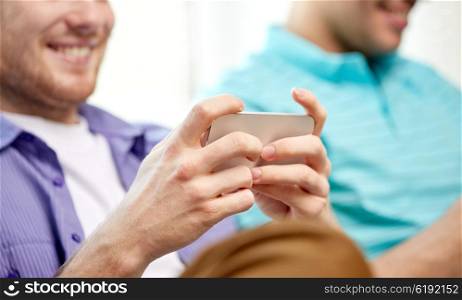 friendship, technology and people concept - close up of happy smiling male friends with smartphones texting or playing games at home