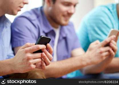 friendship, technology and people concept - close up of happy smiling male friends with smartphones texting at home