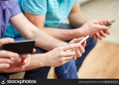 friendship, technology and people concept - close up of male friends with smartphones texting or playing games at home