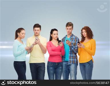 friendship, technology and people concept - group of serious teenagers with smartphones over gray background with laser light