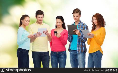 friendship, technology and people concept - group of smiling teenagers with smartphones and tablet pc computers over green background