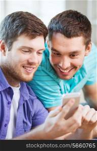 friendship, technology, drinks and home concept - smiling male friends with smartphone at home