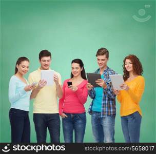 friendship, technology, education, school and people concept - group of smiling teenagers with smartphones and tablet pc computers over green board background