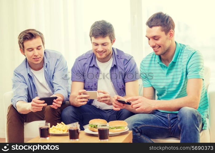 friendship, technology, food and leisure concept - smiling friends taking picture of food with smartphone camera at home
