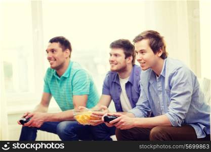 friendship, technology, games and home concept - smiling male friends playing video games at home