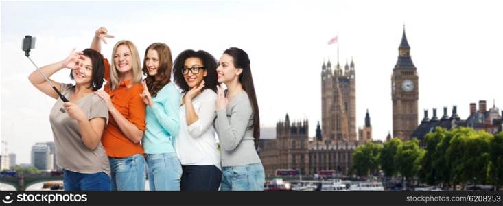 friendship, technology, travel, tourism and people concept - group of happy different size women taking picture with smartphoone on selfie stick over london city and big ben tower background