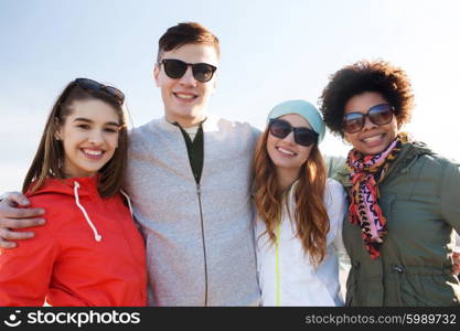 friendship, tourism, travel and people concept - group of happy teenage friends in sunglasses hugging outdoors