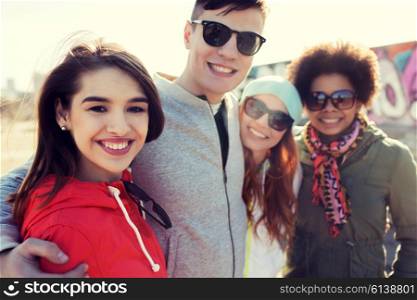friendship, tourism, travel and people concept - group of happy teenage friends in sunglasses hugging outdoors