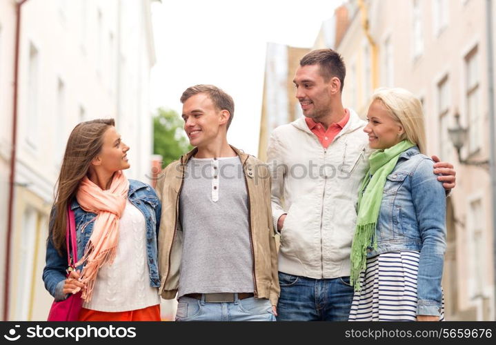 friendship, travel and vacation concept - group of smiling friends walking in the city