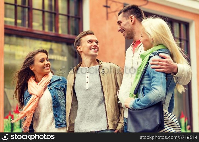 friendship, travel and vacation concept - group of smiling friends walking in the city