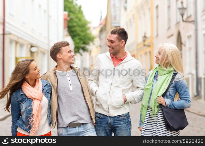 friendship, travel and vacation concept - group of smiling friends walking in the city