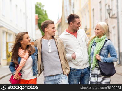 friendship, travel and vacation concept - group of smiling friends walking in the city