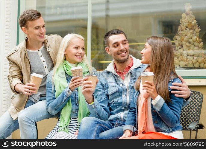 friendship, travel, drink and vacation concept - group of smiling friends with take away coffee