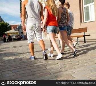 friendship, travel, tourism, summer vacation and people concept - close up of teenage friends walking in city from back