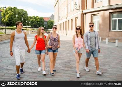 friendship, travel, tourism, summer vacation and people concept - group of smiling teenagers walking in the city