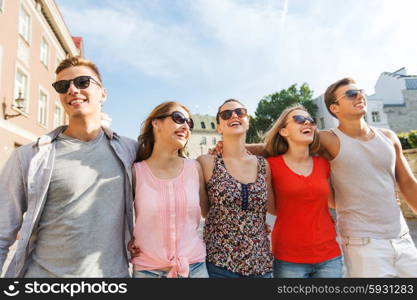 friendship, travel, tourism, summer vacation and people concept - group of smiling teenagers walking in city