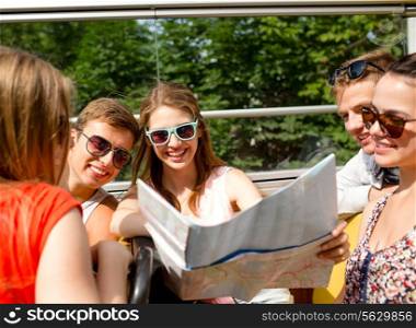 friendship, travel, vacation, summer and people concept - group of smiling friends with map traveling by tour bus