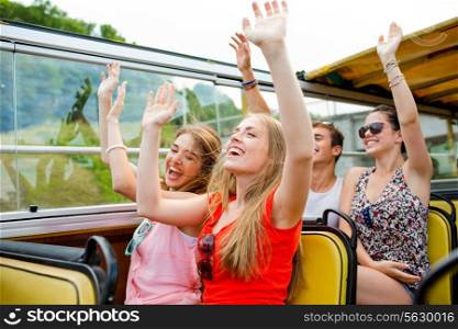 friendship, travel, vacation, summer and people concept - group of smiling friends traveling by tour bus and waving hands