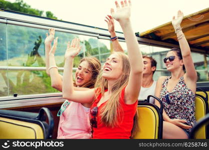 friendship, travel, vacation, summer and people concept - group of smiling friends traveling by tour bus and waving hands