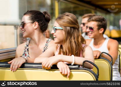 friendship, travel, vacation, summer and people concept - group of smiling friends traveling by tour bus