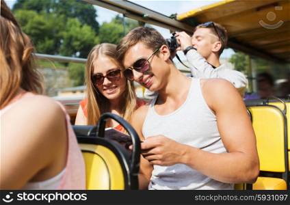 friendship, travel, vacation, summer and people concept - smiling couple in sunglasses with guidebook traveling by tour bus