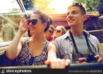 friendship, travel, vacation, summer and people concept - smiling couple with camera traveling by tour bus