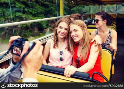 friendship, travel, vacation, summer and people concept - smiling friends with camera traveling by tour bus