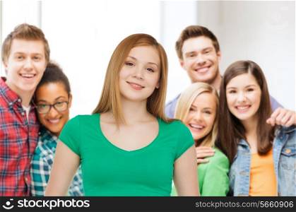 friendship, youth and people concept - group of smiling multiracial teenagers over classroom background