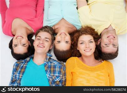 friendship, youth and people - group of smiling teenagers lying on floor