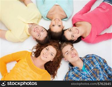 friendship, youth and people - group of smiling teenagers lying on floor in circle